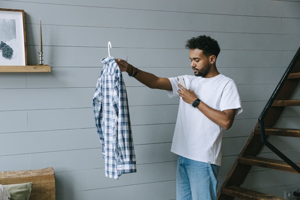 Homme photographiant une chemise à carreaux sur cintre